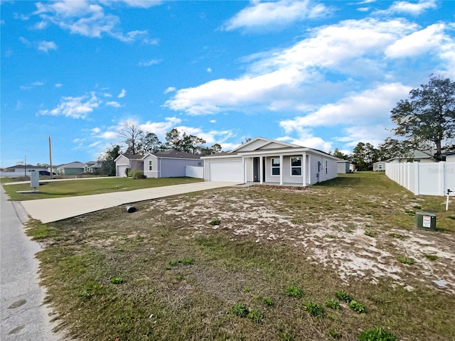 view of front of house featuring a garage, a front yard, concrete driveway, and fence