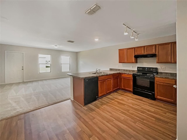 kitchen featuring under cabinet range hood, a peninsula, a sink, visible vents, and black appliances