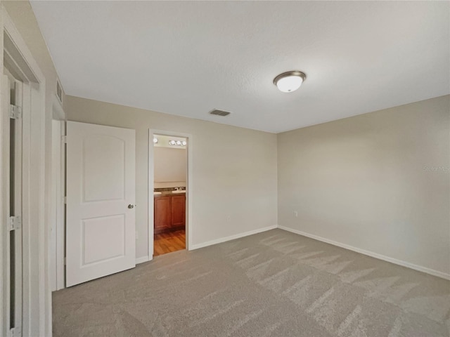 unfurnished bedroom with carpet, visible vents, connected bathroom, and baseboards