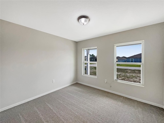 spare room featuring carpet floors and baseboards