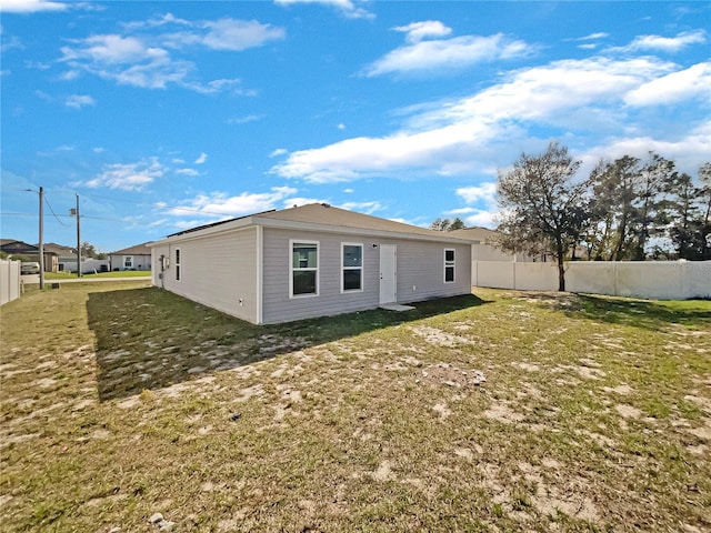 back of property featuring a yard and fence