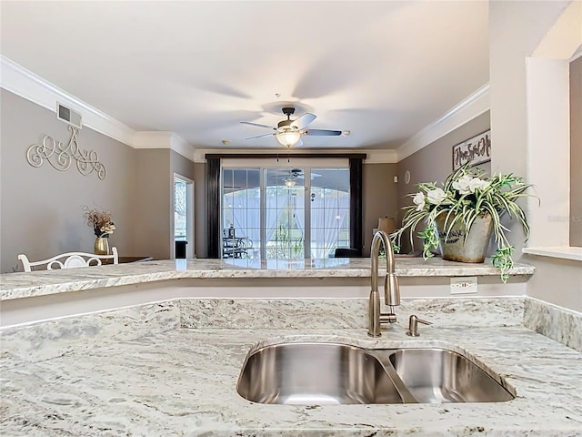 kitchen featuring ornamental molding, a sink, visible vents, and light stone countertops