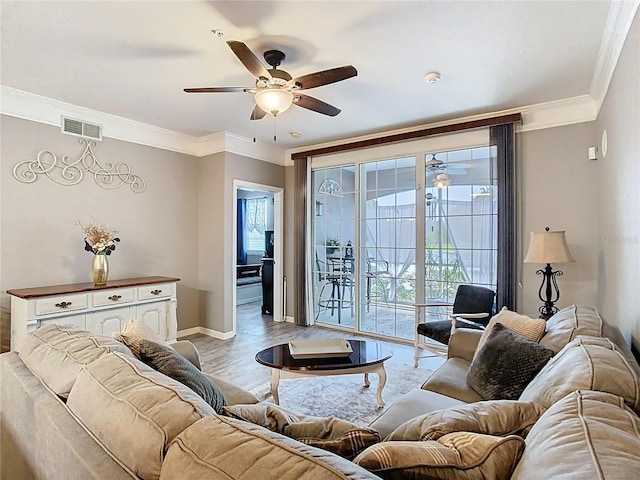 living room with baseboards, light wood-style flooring, visible vents, and crown molding