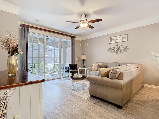 living area with light wood finished floors, ceiling fan, ornamental molding, and baseboards