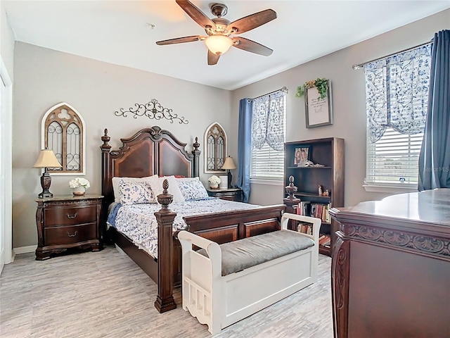 bedroom with a ceiling fan, multiple windows, and light wood-style flooring