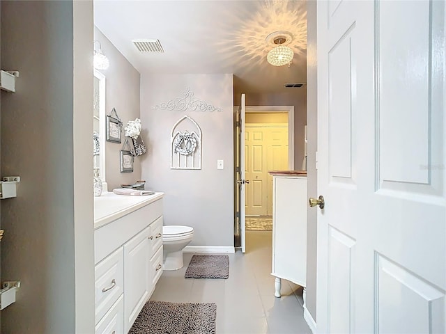 bathroom with toilet, vanity, visible vents, and baseboards