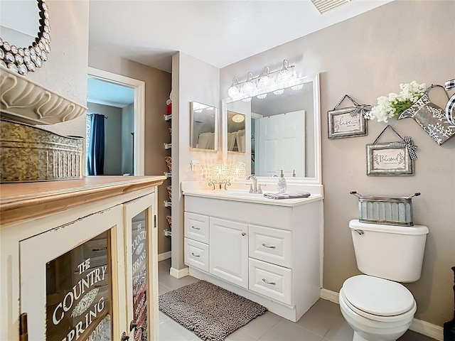 bathroom featuring tile patterned flooring, baseboards, vanity, and toilet