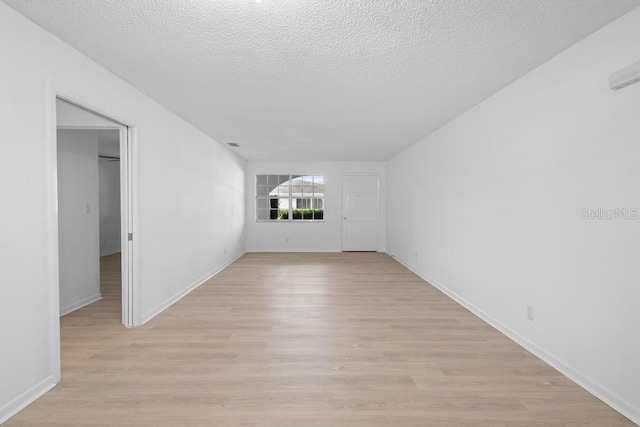 unfurnished room with light wood-style floors, a textured ceiling, and baseboards