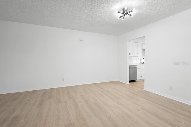 spare room featuring a textured ceiling, light wood-type flooring, and baseboards