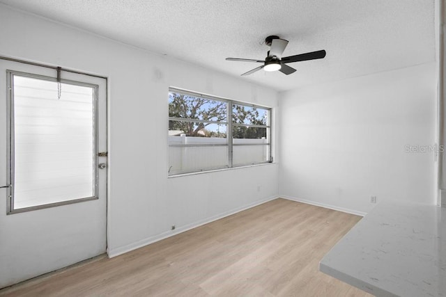 empty room with light wood-type flooring, ceiling fan, and a textured ceiling