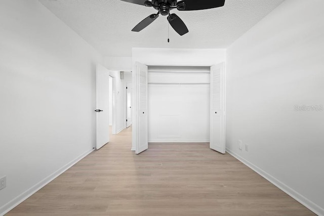 unfurnished bedroom with light wood-style flooring, a closet, baseboards, and a textured ceiling