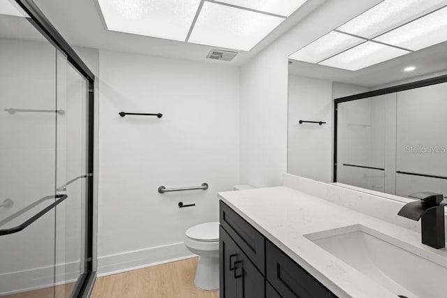 bathroom featuring a stall shower, visible vents, toilet, wood finished floors, and vanity