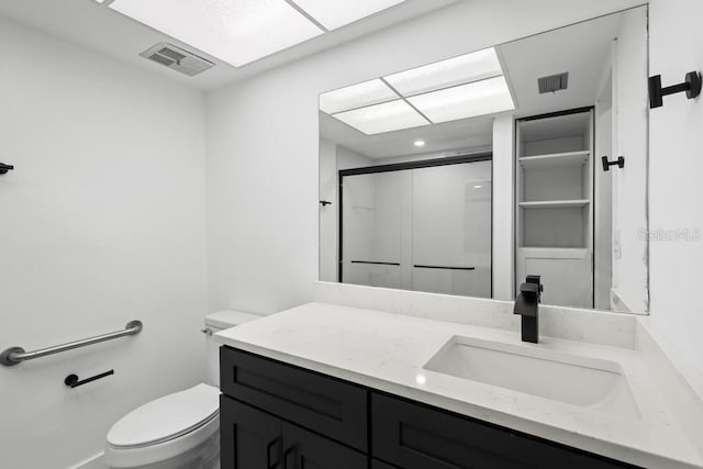 bathroom with toilet, an enclosed shower, vanity, and visible vents