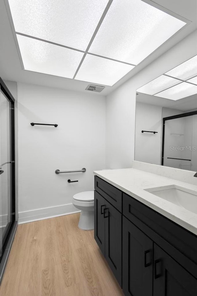 full bath with toilet, wood finished floors, vanity, visible vents, and a stall shower