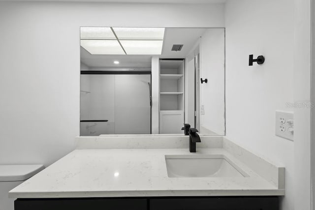 bathroom with a shower with shower door, visible vents, vanity, and toilet