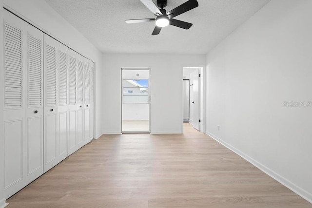 unfurnished bedroom with a textured ceiling, a closet, light wood-style flooring, and baseboards