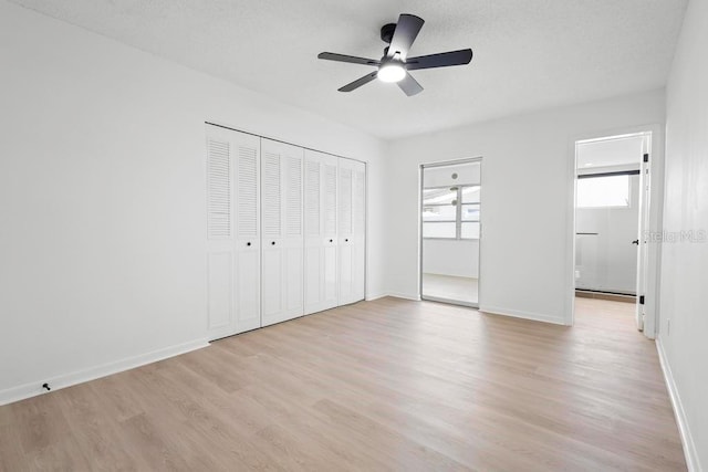 unfurnished bedroom with a textured ceiling, a closet, light wood-style flooring, and baseboards