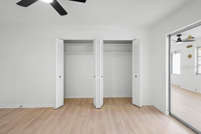 unfurnished bedroom featuring multiple closets, a ceiling fan, a textured ceiling, light wood-type flooring, and baseboards