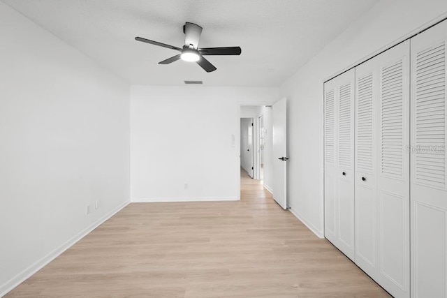 unfurnished bedroom with a closet, visible vents, a ceiling fan, light wood-type flooring, and baseboards