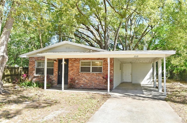 view of front of home with driveway, fence, an attached carport, and brick siding