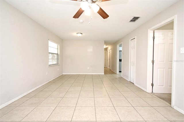 empty room featuring light tile patterned floors, baseboards, visible vents, and ceiling fan