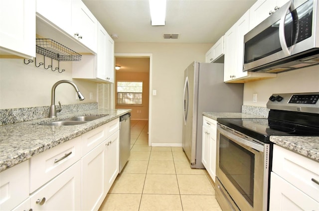 kitchen featuring light tile patterned floors, stainless steel appliances, visible vents, white cabinetry, and a sink