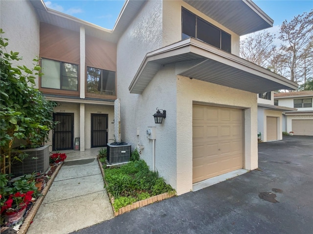 view of front of property with a garage, cooling unit, and stucco siding