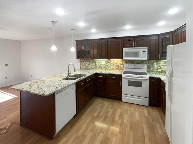 kitchen featuring a peninsula, white appliances, a sink, dark brown cabinets, and light wood-type flooring