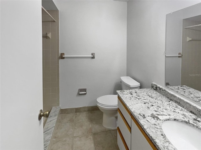 full bathroom featuring a tile shower, vanity, toilet, and tile patterned floors