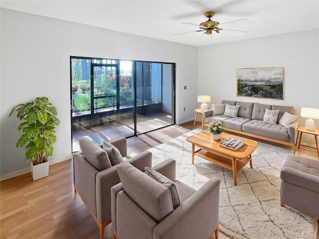 living area featuring light wood finished floors, baseboards, and a ceiling fan