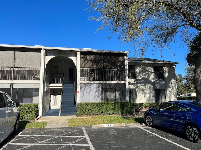 view of property with uncovered parking and stairs