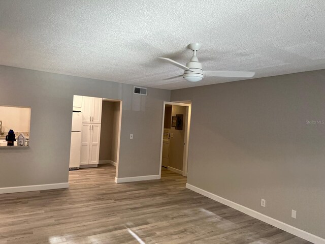 unfurnished room featuring visible vents, ceiling fan, baseboards, and wood finished floors