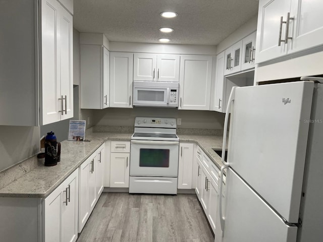 kitchen with recessed lighting, white cabinetry, a textured ceiling, light wood-type flooring, and white appliances