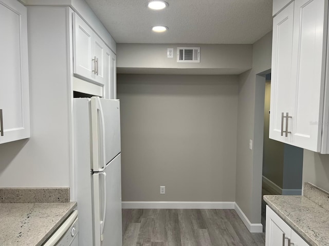 kitchen featuring wood finished floors, visible vents, baseboards, white cabinetry, and freestanding refrigerator