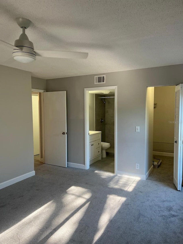 unfurnished bedroom with light colored carpet, visible vents, ensuite bathroom, a textured ceiling, and baseboards