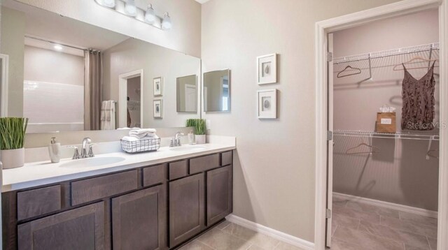 bathroom featuring double vanity, tile patterned flooring, baseboards, and a sink