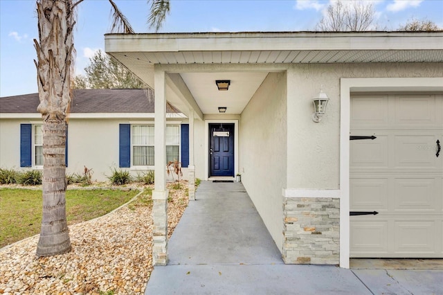 doorway to property with an attached garage, a shingled roof, and stucco siding