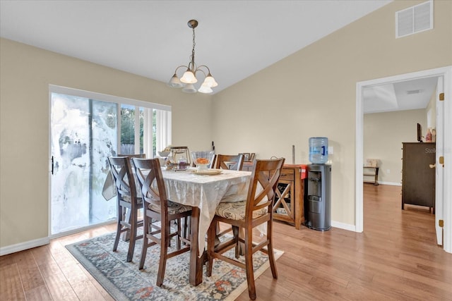 dining space with lofted ceiling, visible vents, baseboards, light wood-type flooring, and an inviting chandelier