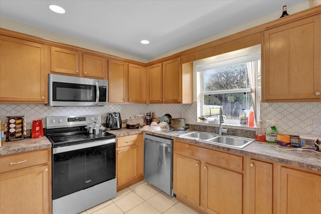 kitchen featuring appliances with stainless steel finishes, tasteful backsplash, a sink, and light tile patterned floors