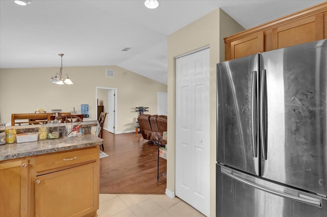 kitchen with light tile patterned floors, visible vents, an inviting chandelier, freestanding refrigerator, and vaulted ceiling