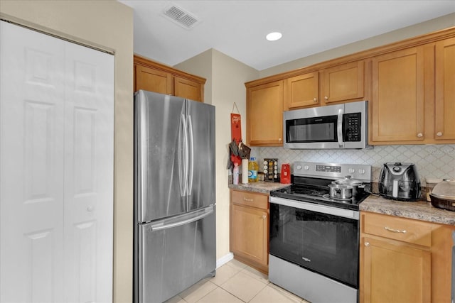 kitchen featuring light tile patterned floors, stainless steel appliances, visible vents, light countertops, and backsplash