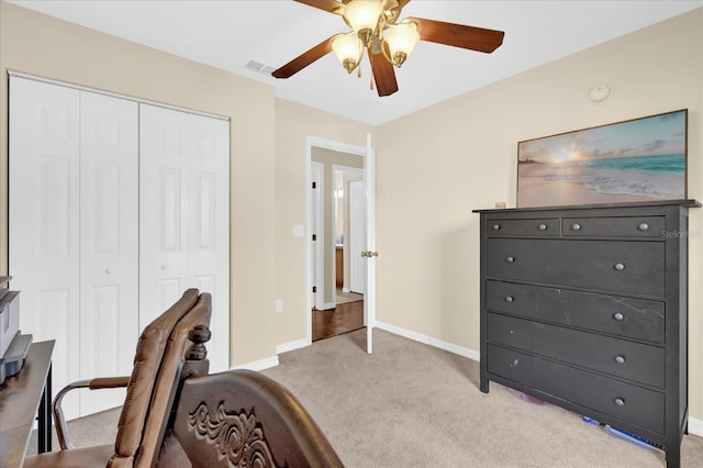 office area featuring light carpet, ceiling fan, visible vents, and baseboards