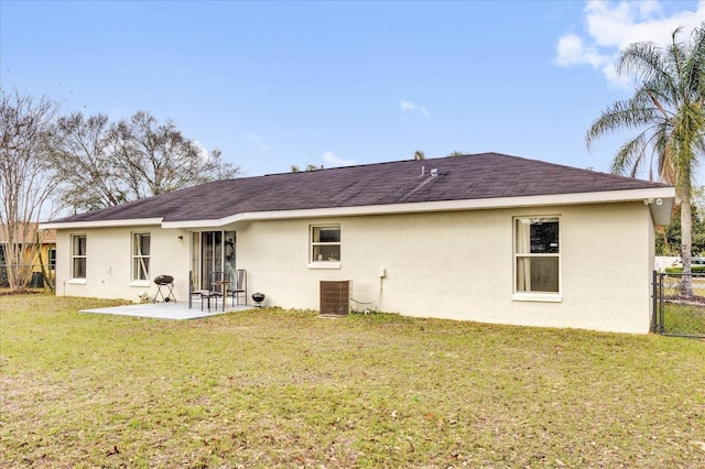 rear view of property featuring central AC, fence, a lawn, stucco siding, and a patio area