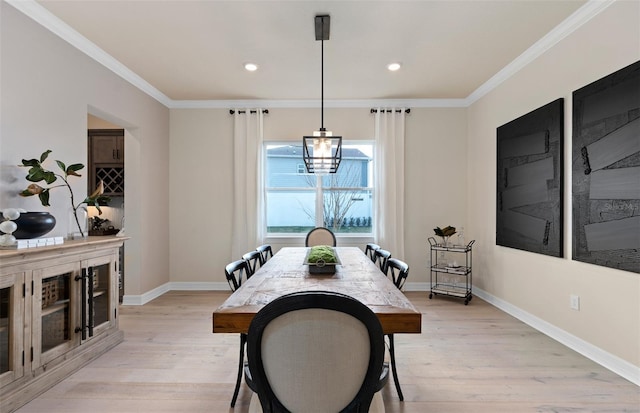 dining room featuring light wood-style floors, crown molding, and baseboards