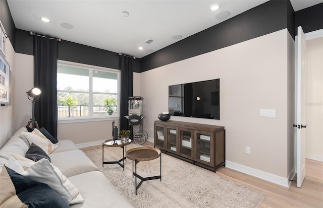 living area with light wood finished floors, recessed lighting, visible vents, and baseboards