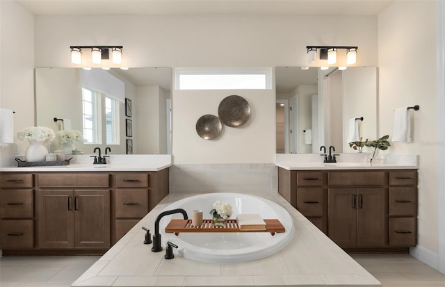 full bathroom featuring two vanities, a garden tub, and a sink