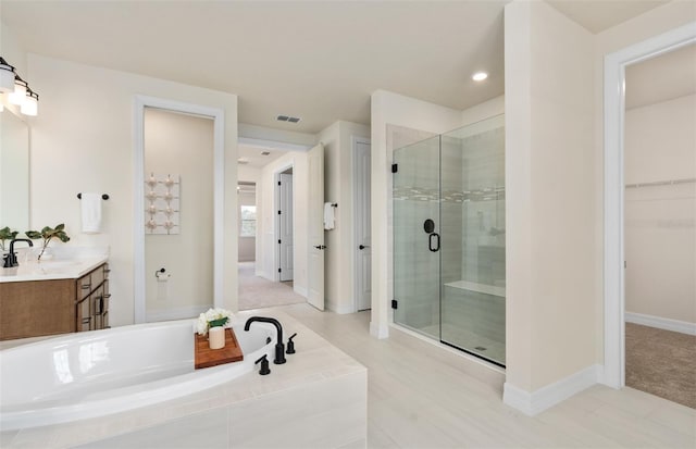 bathroom featuring visible vents, vanity, a spacious closet, a shower stall, and a bath