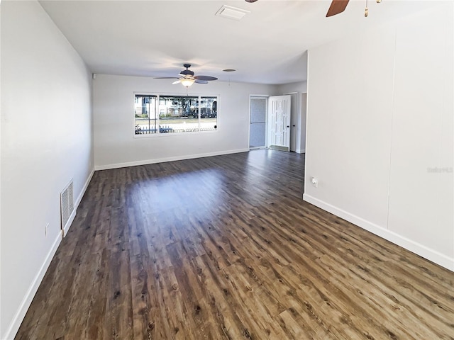 empty room featuring ceiling fan, visible vents, and dark wood-style flooring