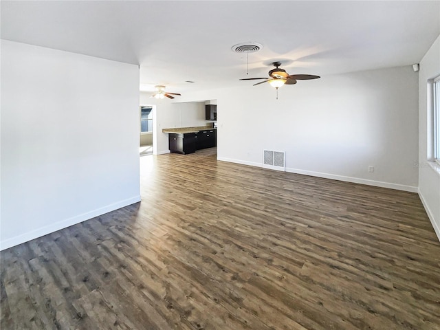 unfurnished living room with visible vents, dark wood finished floors, baseboards, and ceiling fan