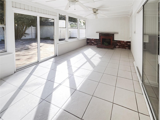 unfurnished sunroom with ceiling fan and a fireplace